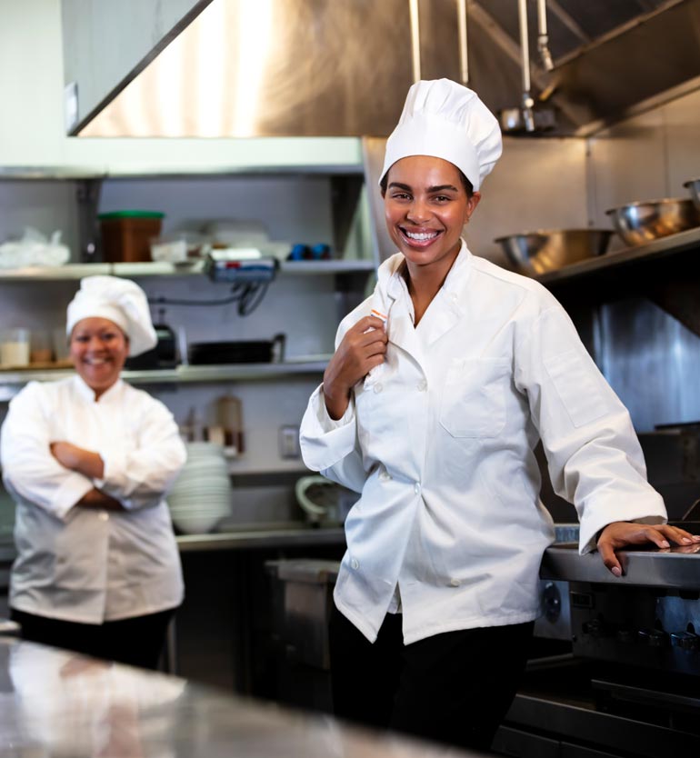 senior-living-chef Chef smiling with colleague in professional kitchen at senior living facility.