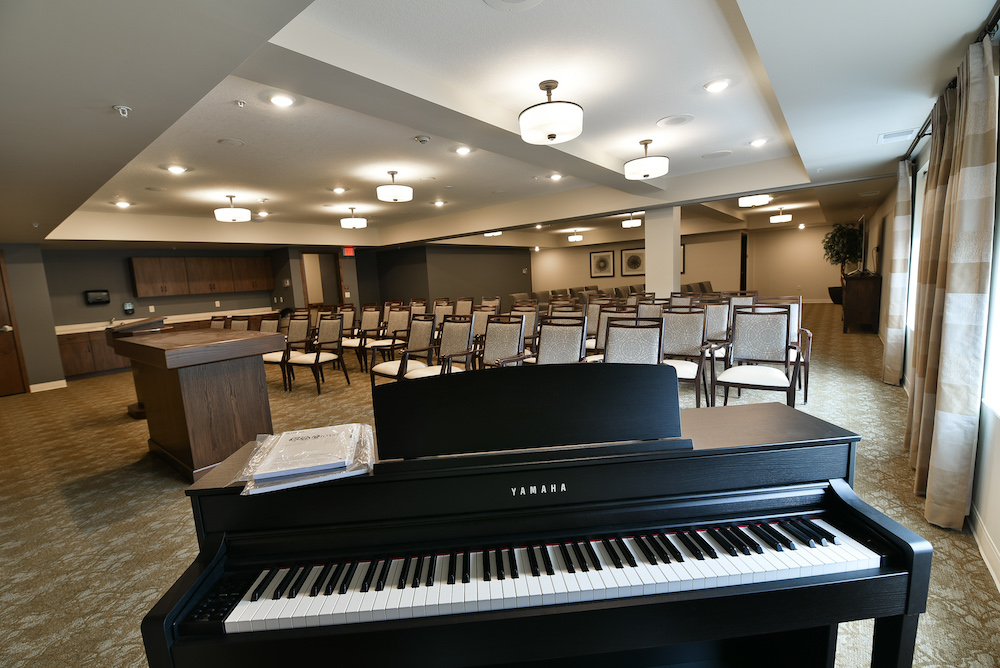 Conference room setup with piano, chairs, and modern lighting fixtures in Havenwood community center.
