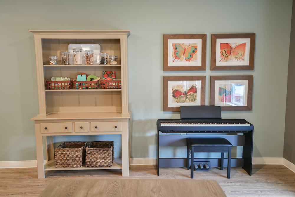Wooden hutch and piano setup, with colorful butterfly artwork above the piano in a cozy room