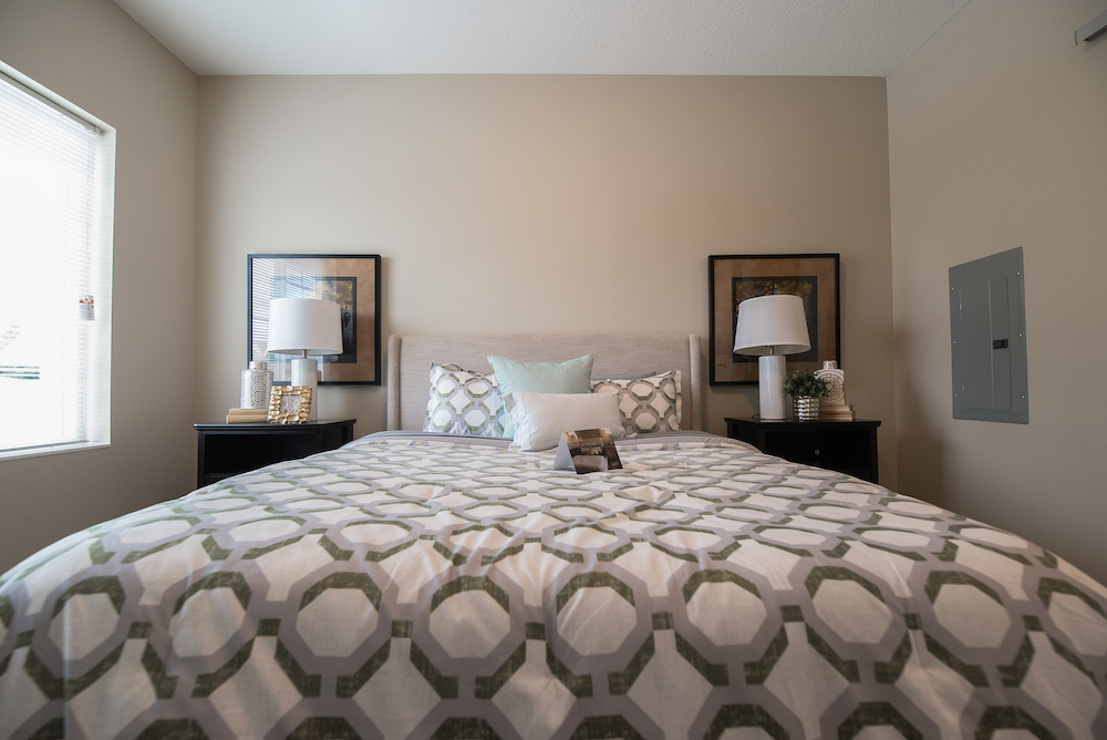 Modern bedroom with patterned comforter, two nightstands, lamps, and framed wall art.