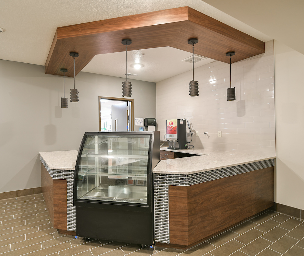 Modern coffee bar with dark wood accents, pendant lighting, and an overhead brown wood panel.