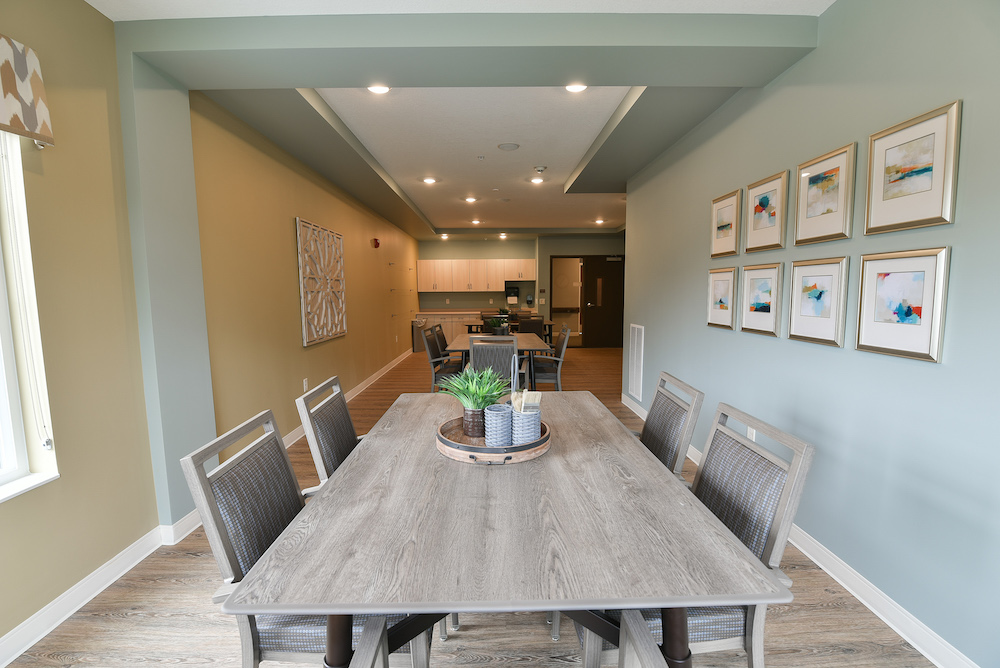 Modern dining room with a long wooden table, chairs, and decorative wall art in the background.