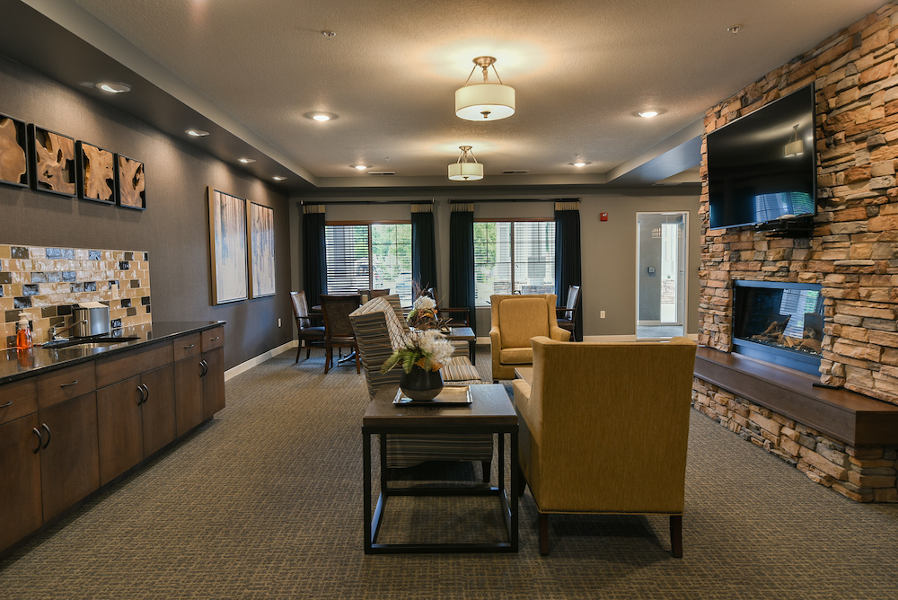 Modern cozy lounge area with comfortable seating, a stone fireplace, and a kitchenette.