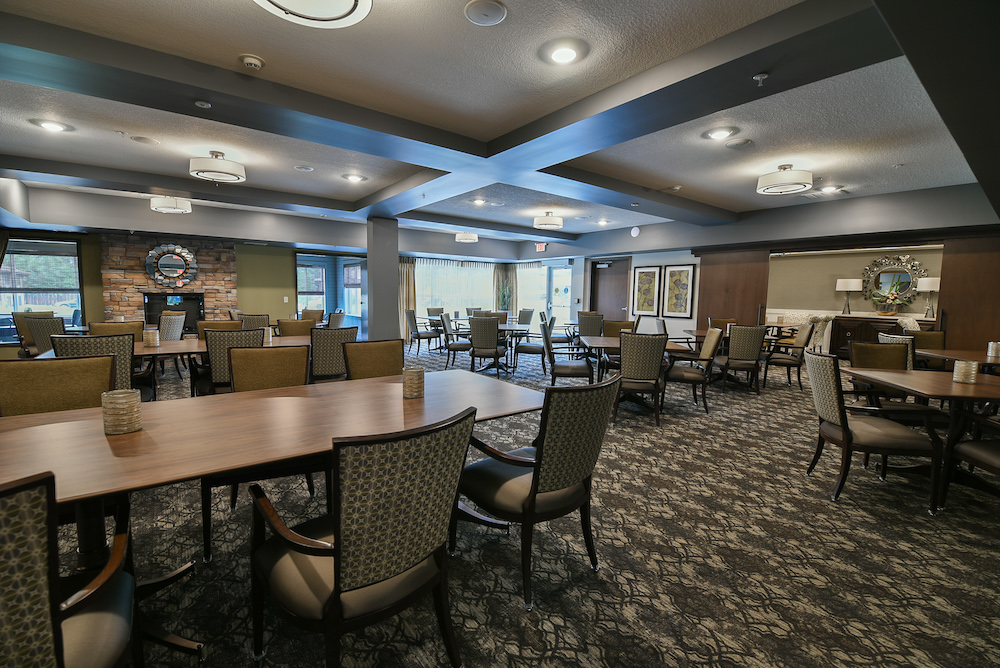 Spacious dining area featuring wooden tables, cushioned chairs, and a cozy fireplace.