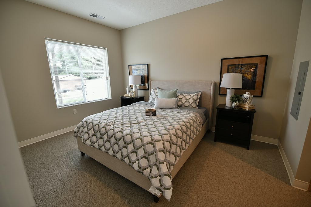Bedroom with large window, two bedside tables, and various decor