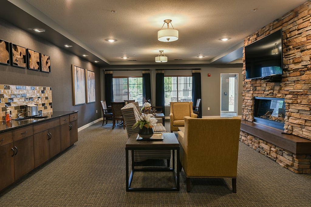 Cozy common living area with seating, stone fireplace, and mounted TV