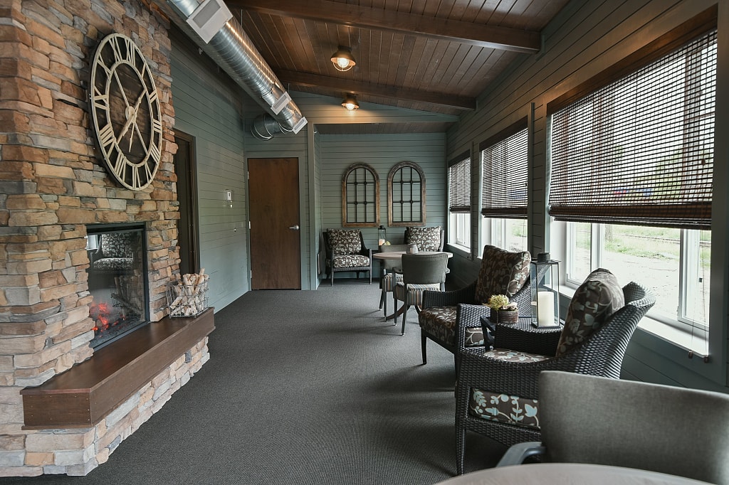 Cozy fireplace surrounded by seating and large clock.